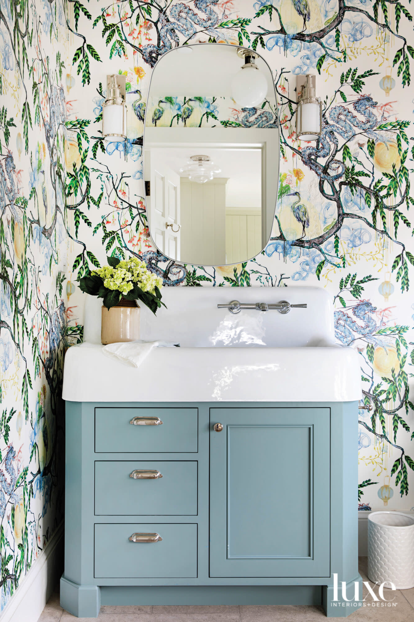 Powder room with blue painted vanity and floral wallpaper