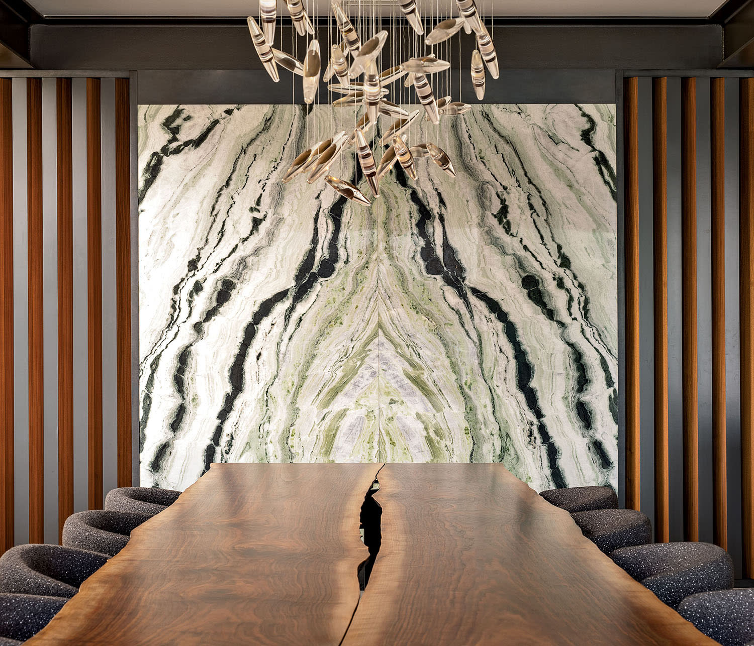 A walnut dining table with sits with chairs on either side leading up to large artwork on the wall.