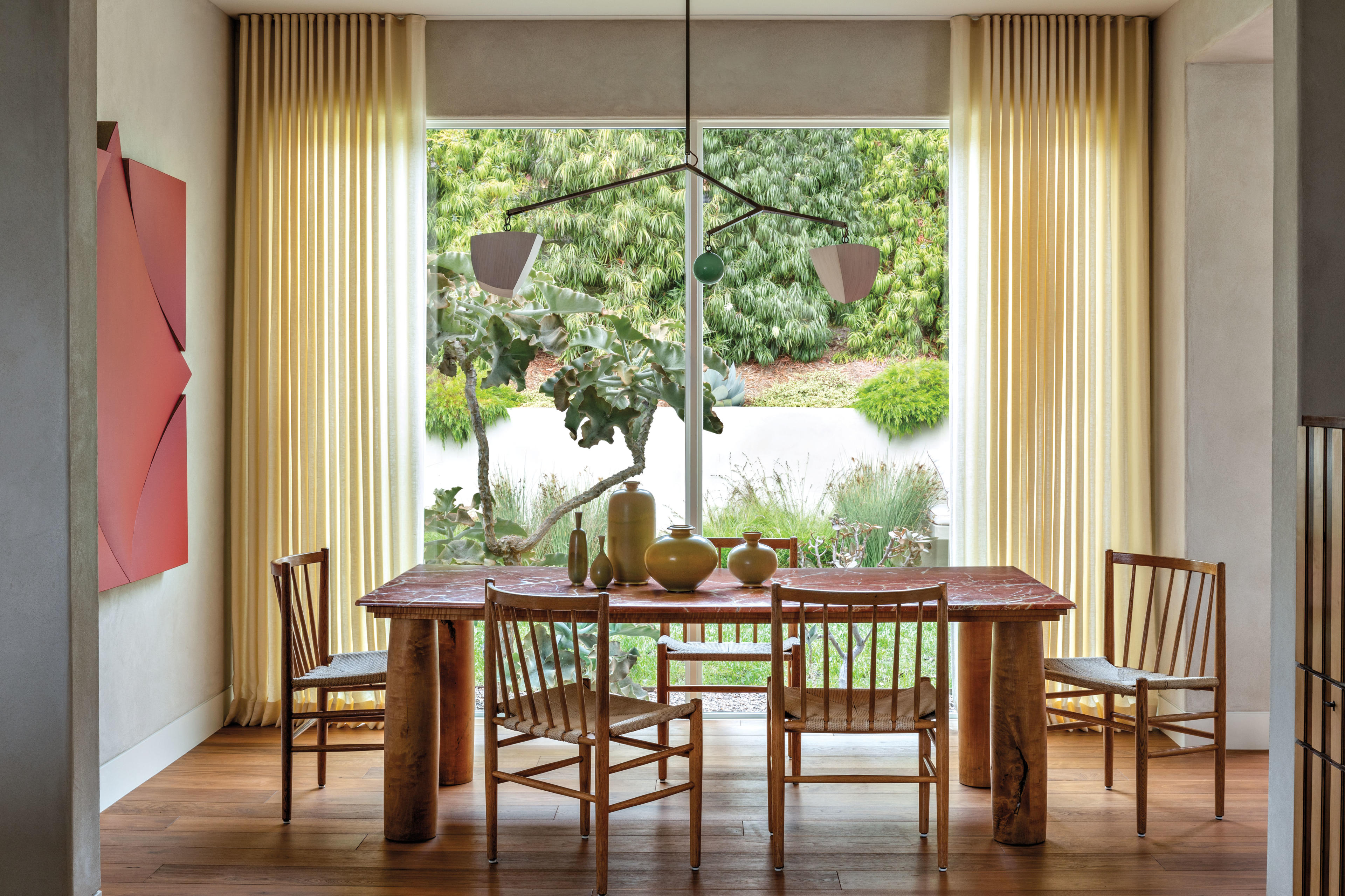 modernist-inspired dining room with red artwork and sheer yellow curtains