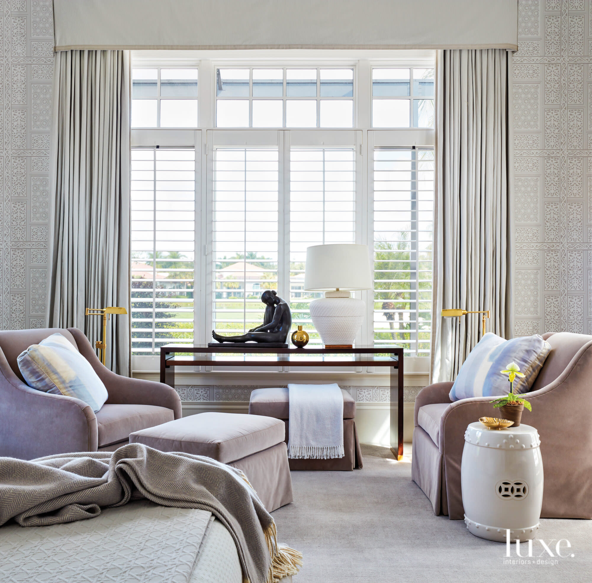 Master bedroom with two purple armchairs and ottomans