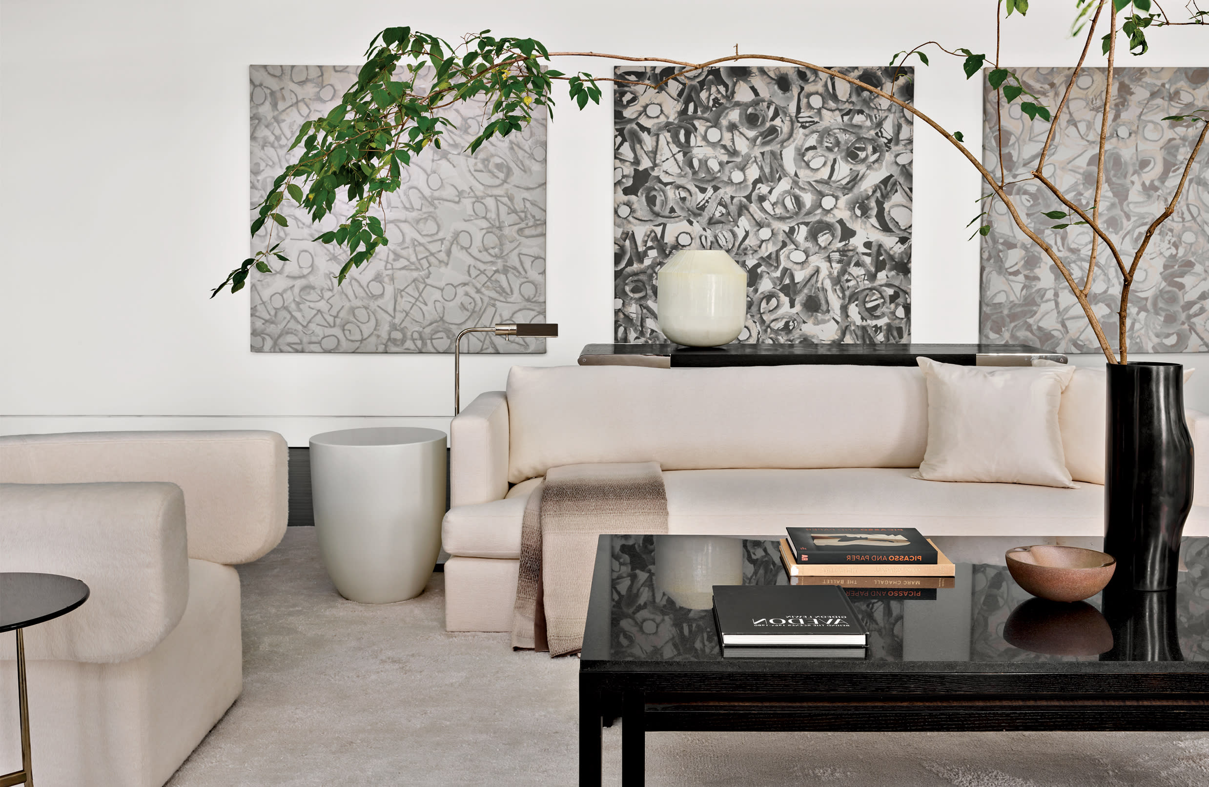 3 Herbert Creecy paintings line the wall above a white sofa in this modern living room