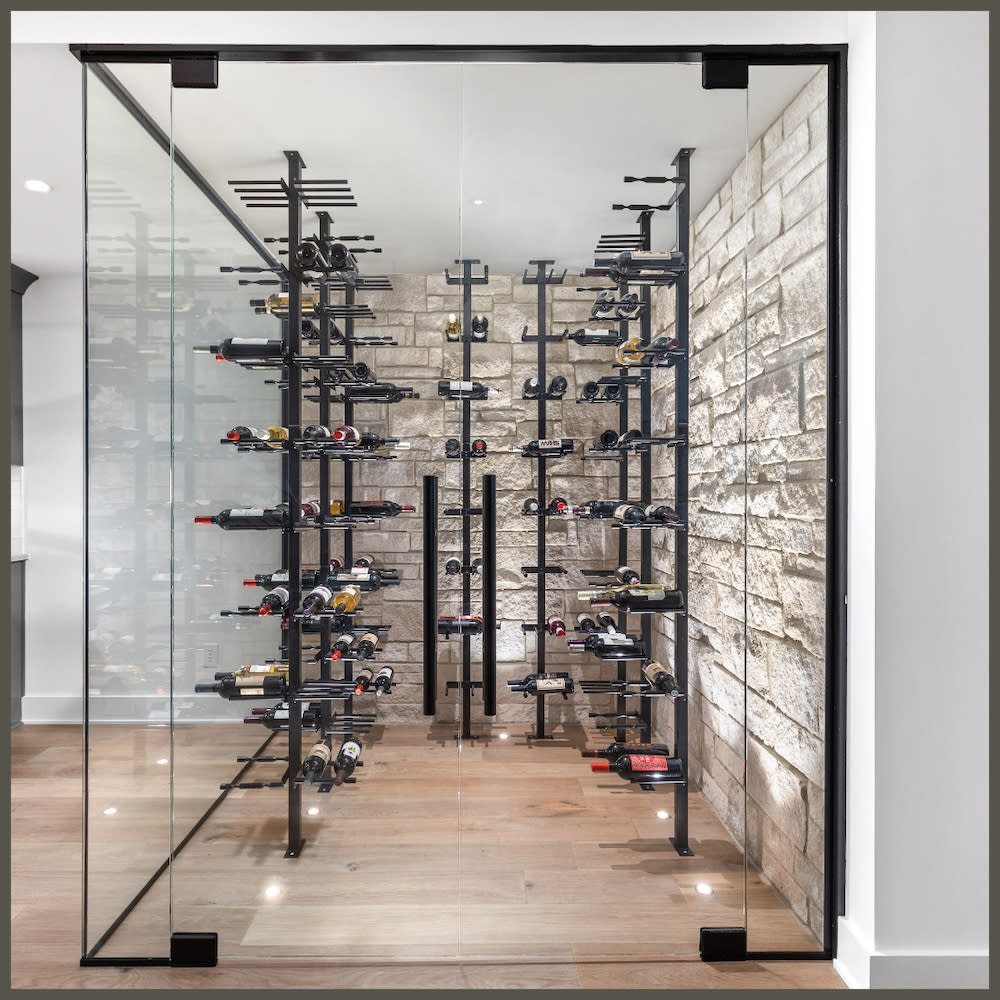 A stylish wine cellar with glass walls, highlighting shelves stocked with a diverse selection of wine bottles.