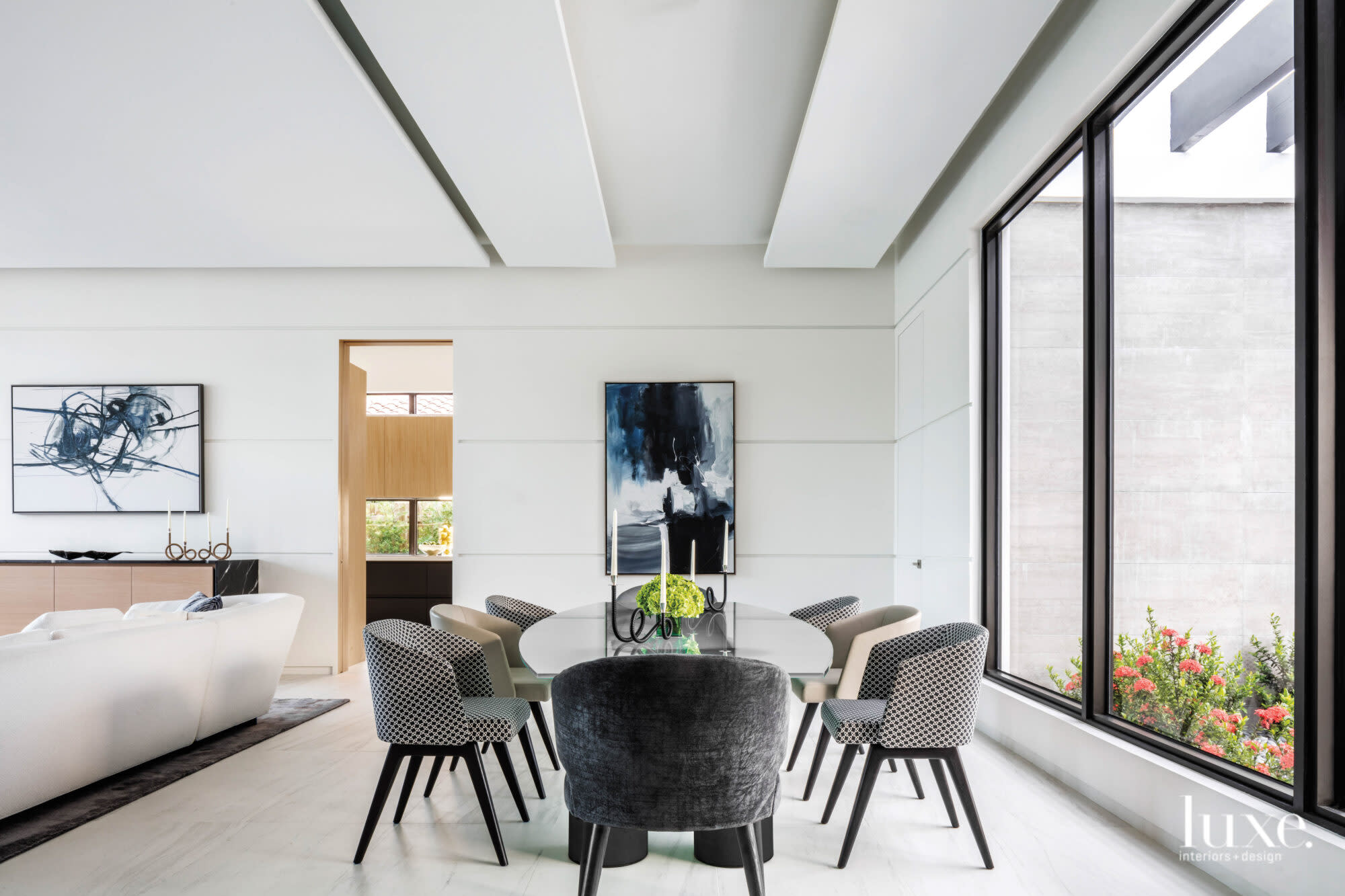 Dining room with leather and suede dining chairs around an antique glass-topped table with black stone base.