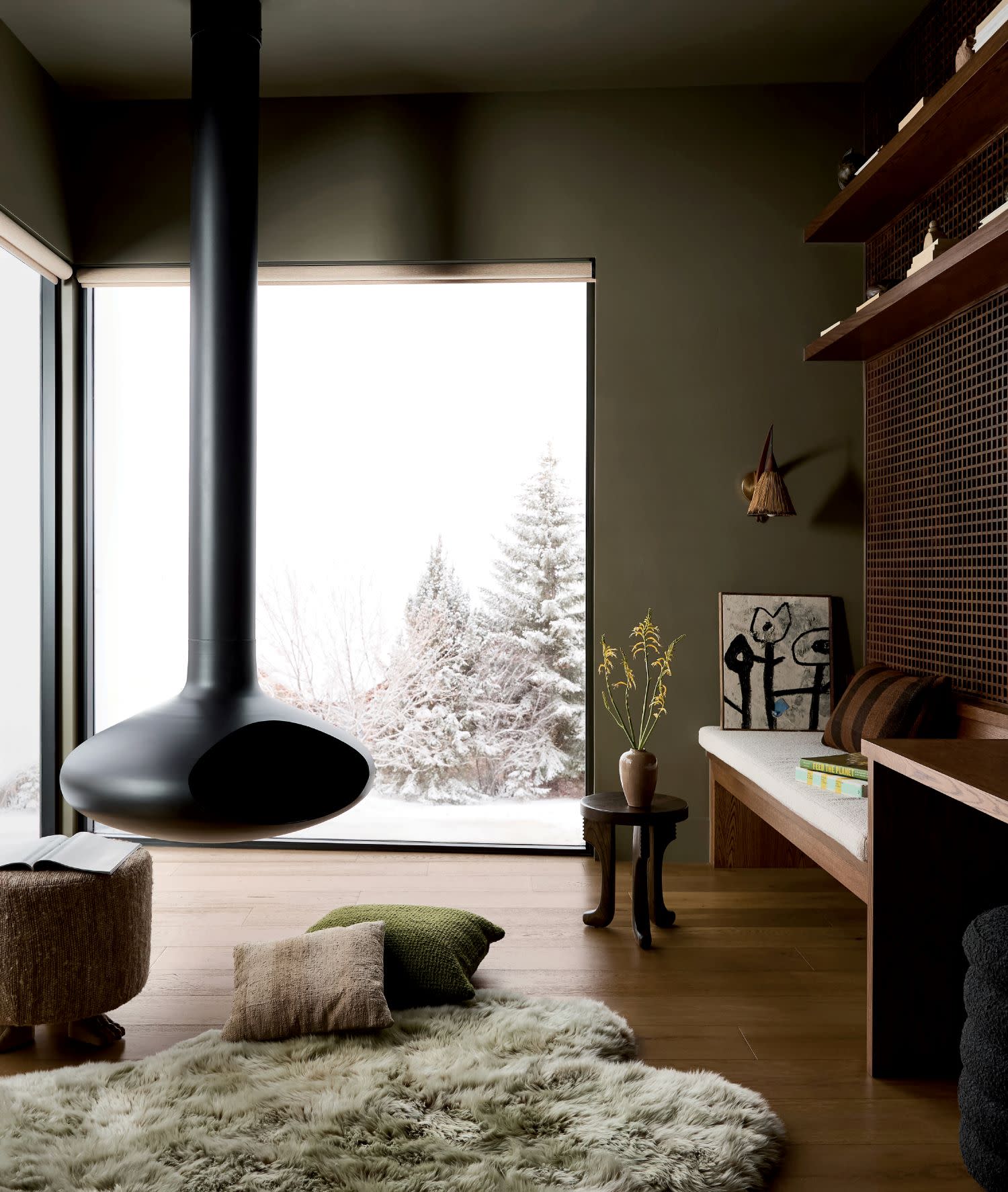Cozy home office with a black suspended fireplace, large snowy window view and a shaggy rug