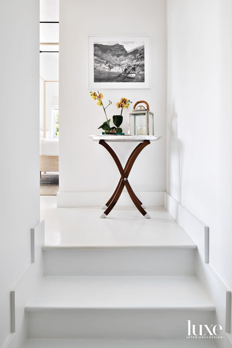 steps to primary bedroom with side table beneath black and white photograph