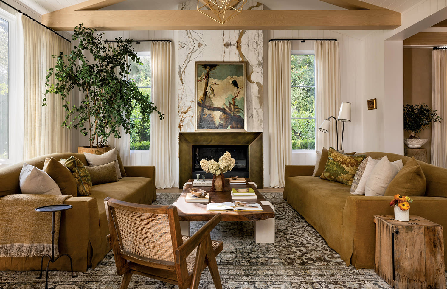 Earth-toned couches sit on either side of a fireplace with artwork hanging above the mantle.