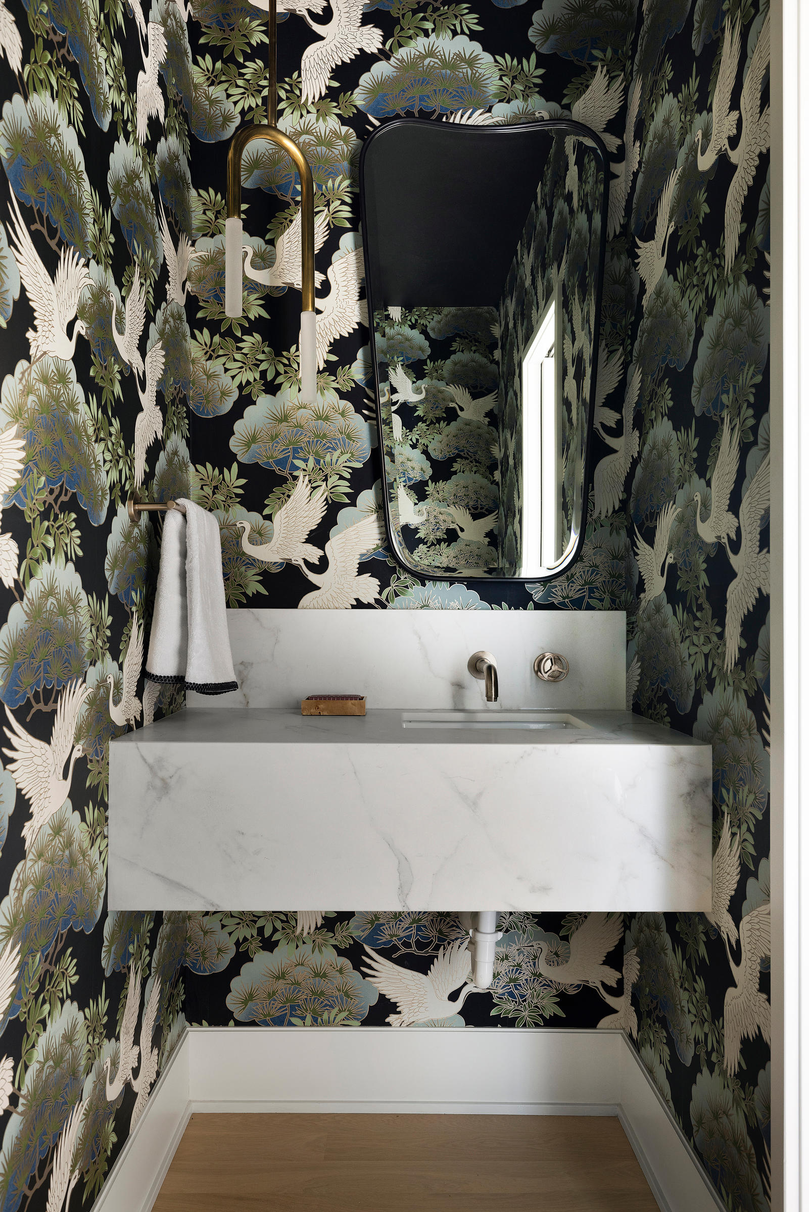 Whimsical wallpaper creates a bold focal point in this charming powder bath, while a sleek marble sink adds a touch of modern sophistication. 
Photography by Spacecrafting 
