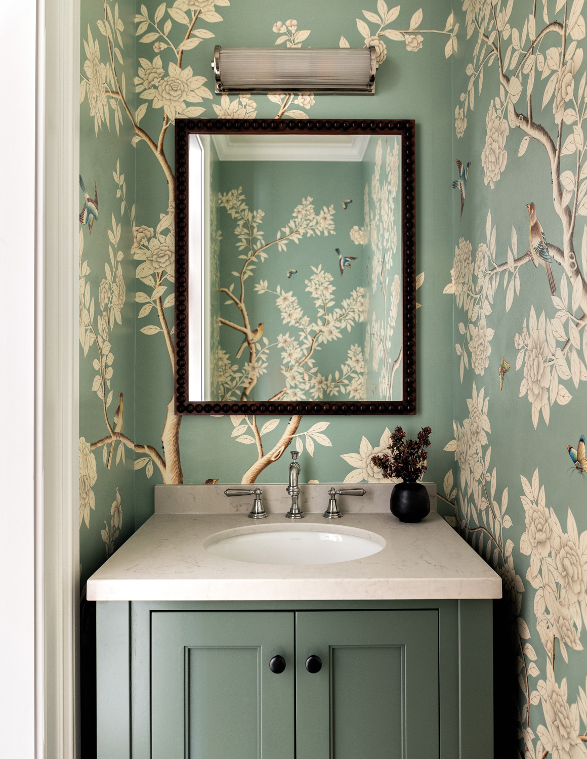 A powder room has flowered wallpaper.