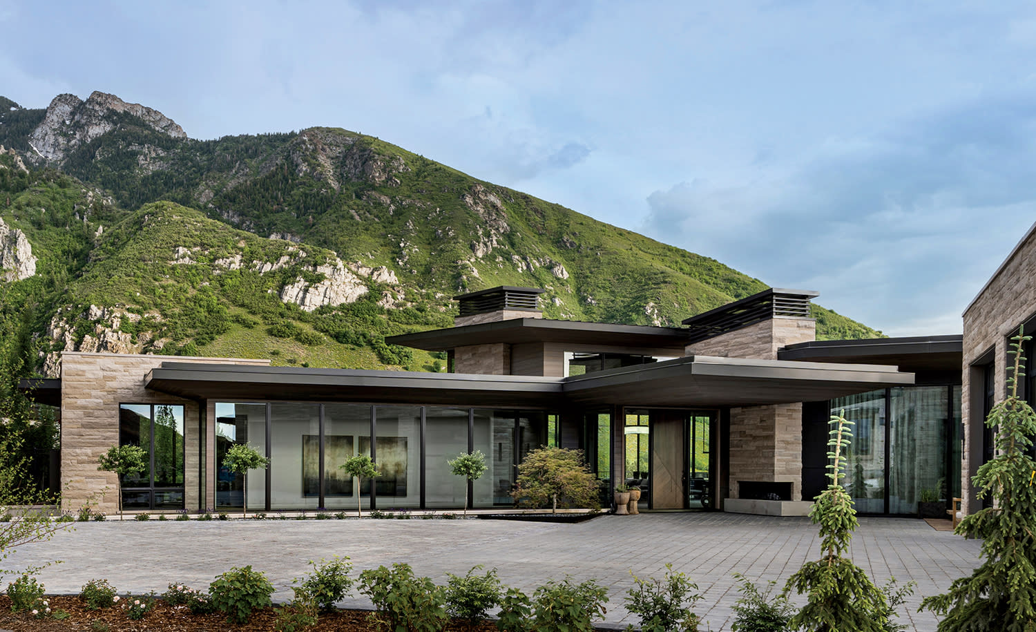 home exterior of limestone, cedar, glass and steel surrounded by dramatic ridges