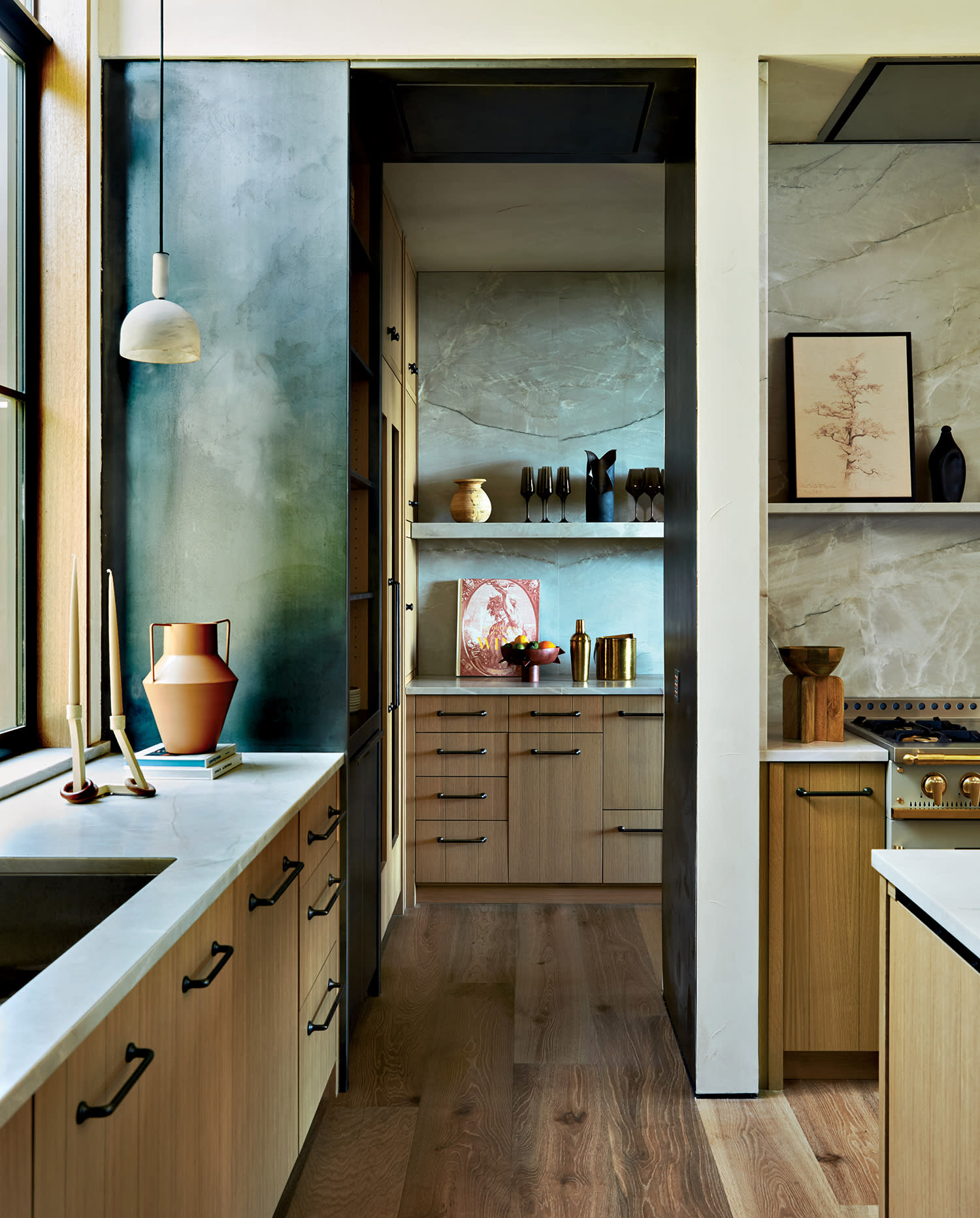 A kitchen and adjoining scullery with white oak cabinets, quartzite countertops and hardwood floors. 