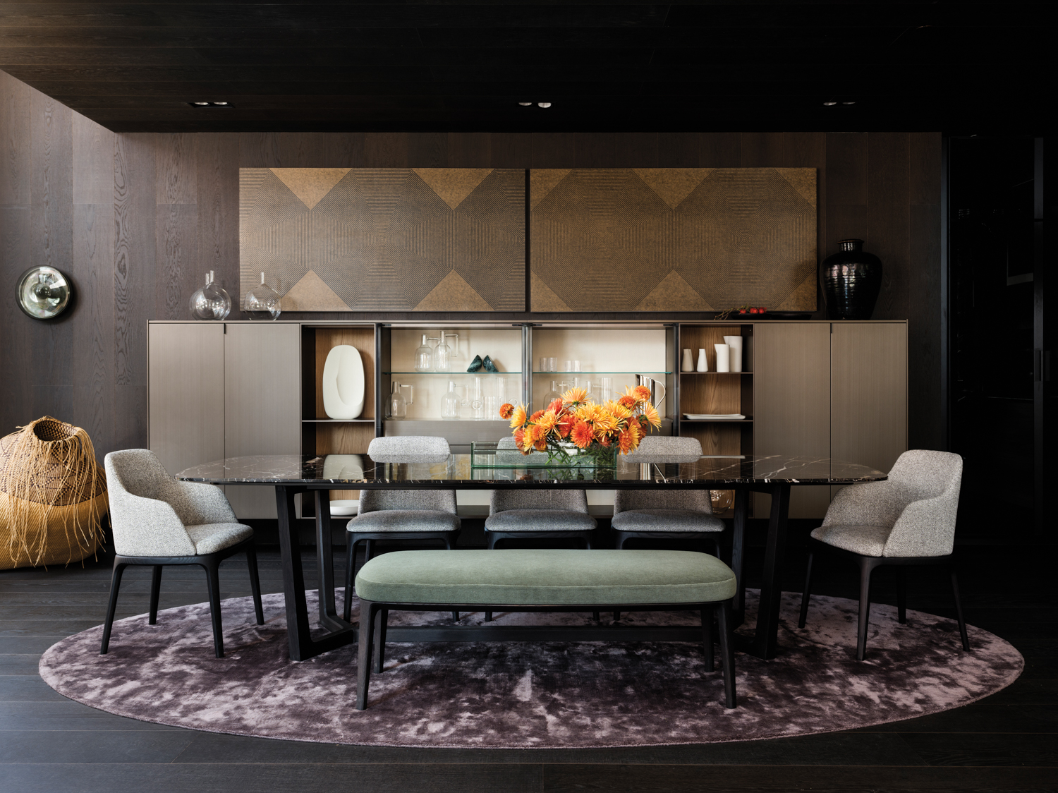 Showroom featuring marble-topped dining table, gray chairs and a green bench in front of a long bar cabinet.