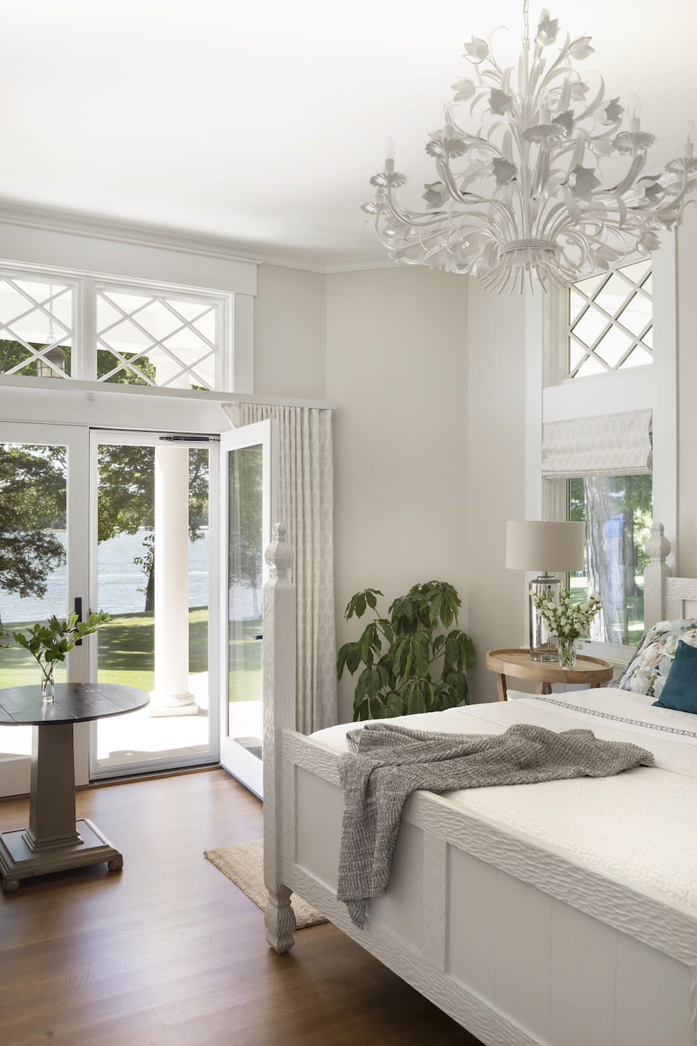 Bright and airy primary bedroom with white, ornate chandelier 