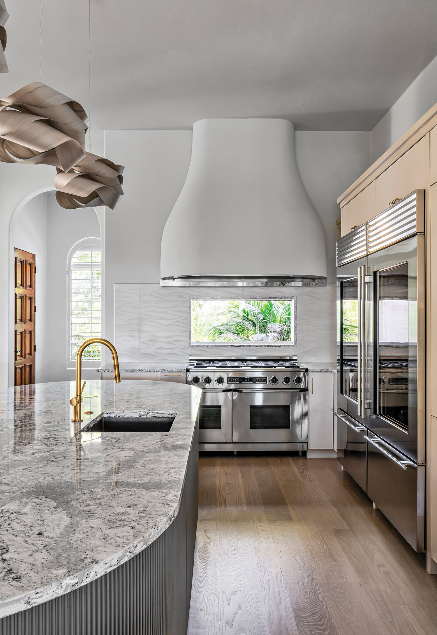 Contemporary kitchen with marble island, gold faucet, and large stainless steel appliances