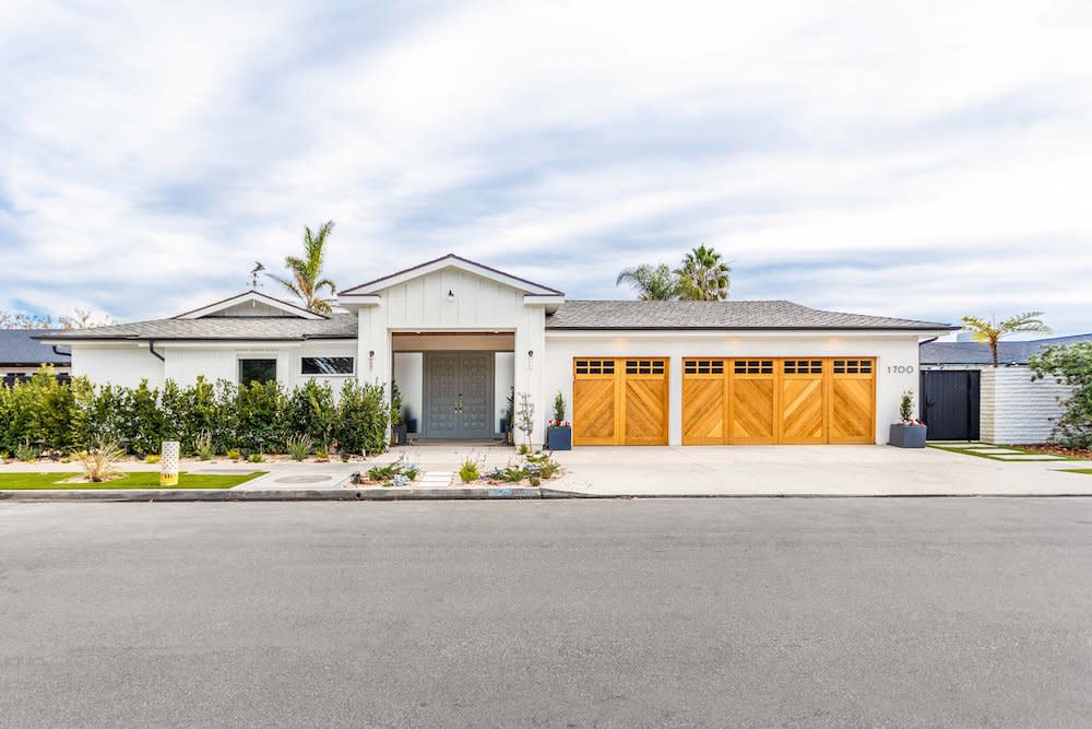 A contemporary white home with clean lines, wood garage doors and large windows, set against a clear blue sky by Kabbany Architecture in Southern California.