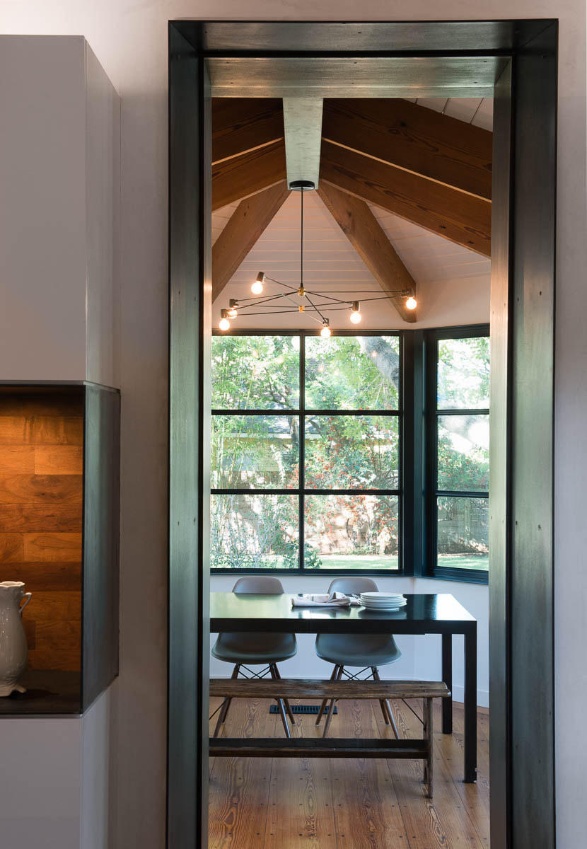 Dining area with vaulted wood ceiling, black-framed windows, and modern chandelier.