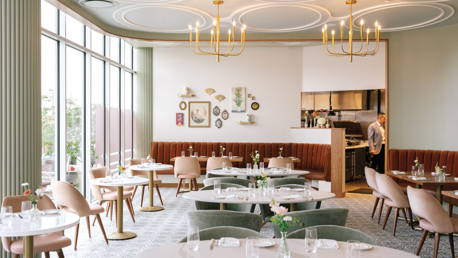 Interior of Noisette restaurant with an antique chandelier, gallery wall, and pink and green seating