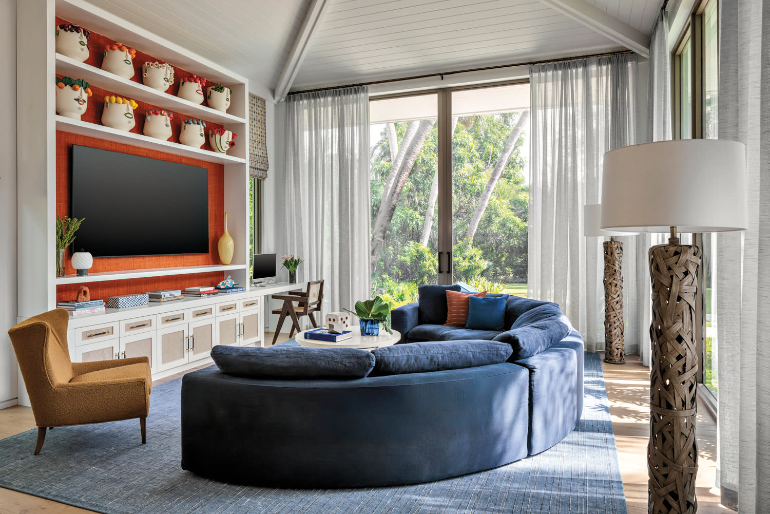 contemporary family room with a blue sectional and playful ceramics displayed against a red backdrop