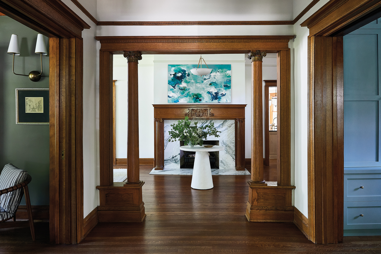 entry to a Victorian home with wood moldings and a marble fireplace with a wood mantle