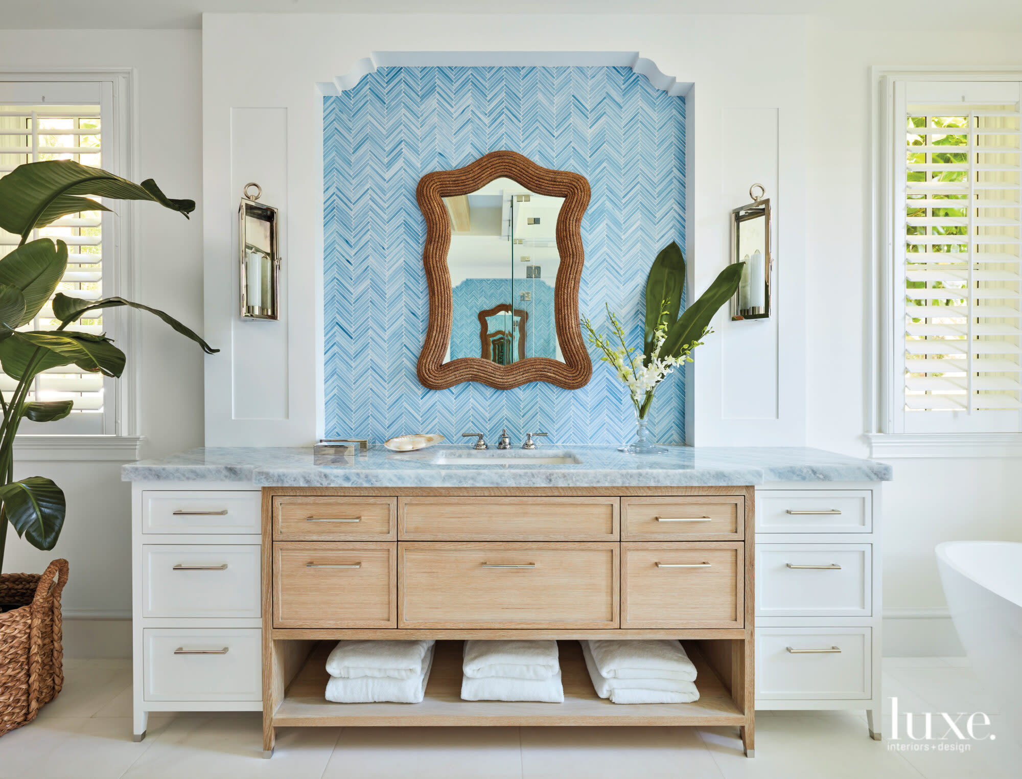 Bathroom with wood-frame mirror hung against a blue-tile wall.