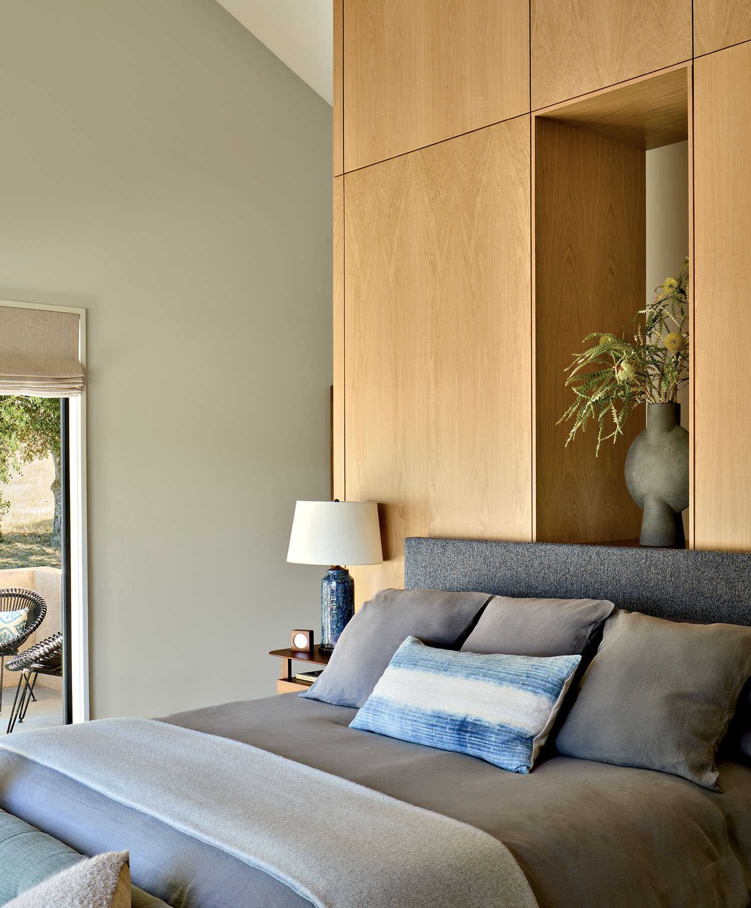 contemporary bedroom with gray linens and light wood finishes