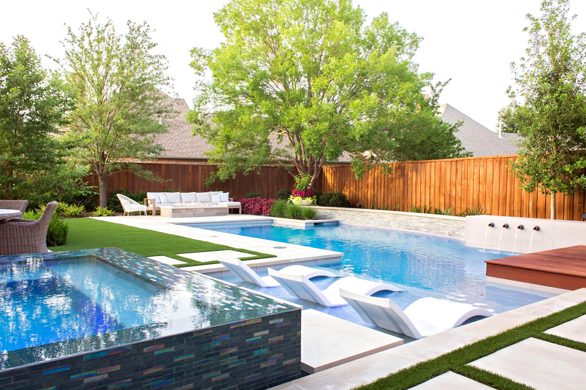 Backyard pool with sun loungers, spa, and wood fencing