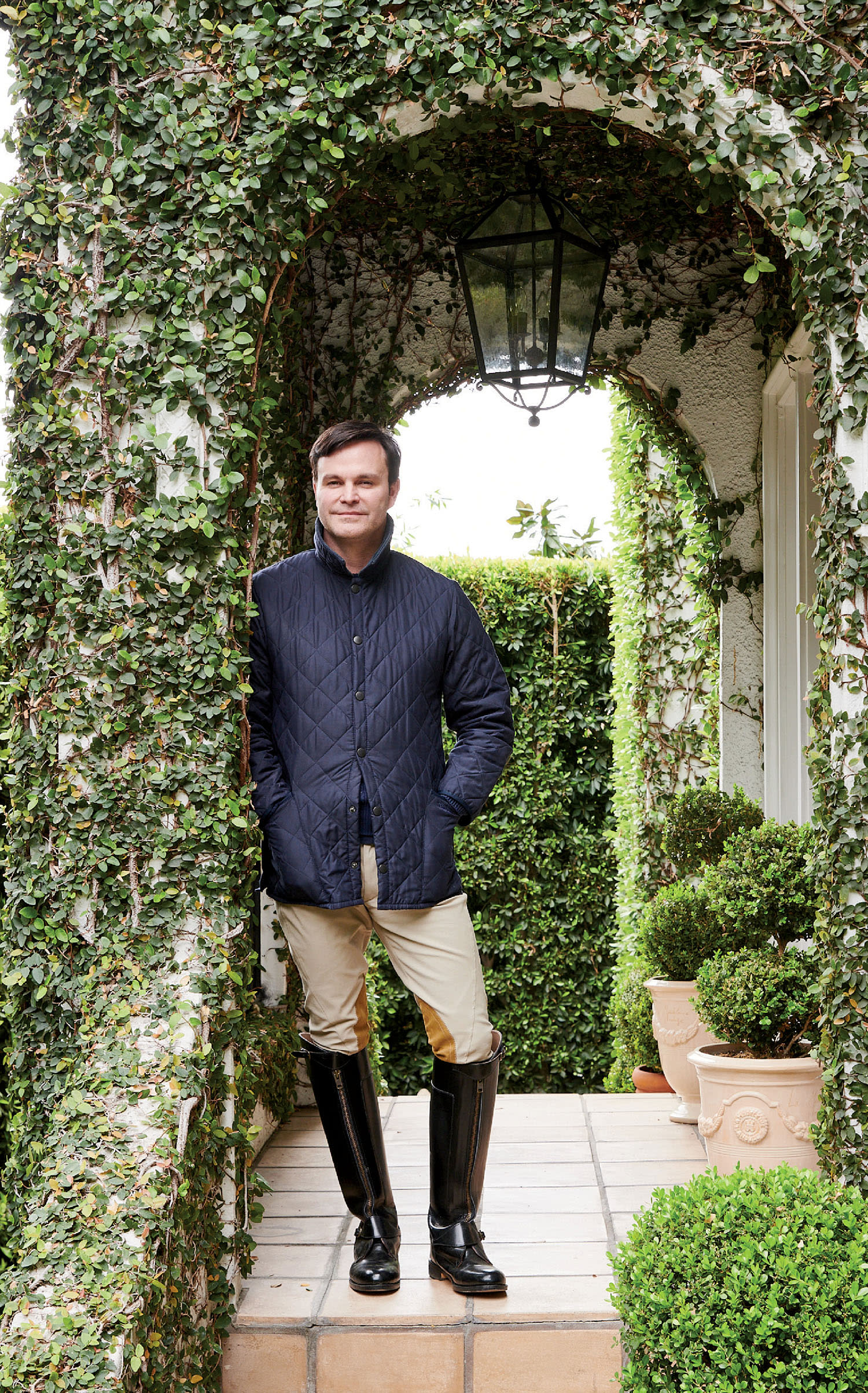 Mark Sikes poses near an archway covered in ivy.