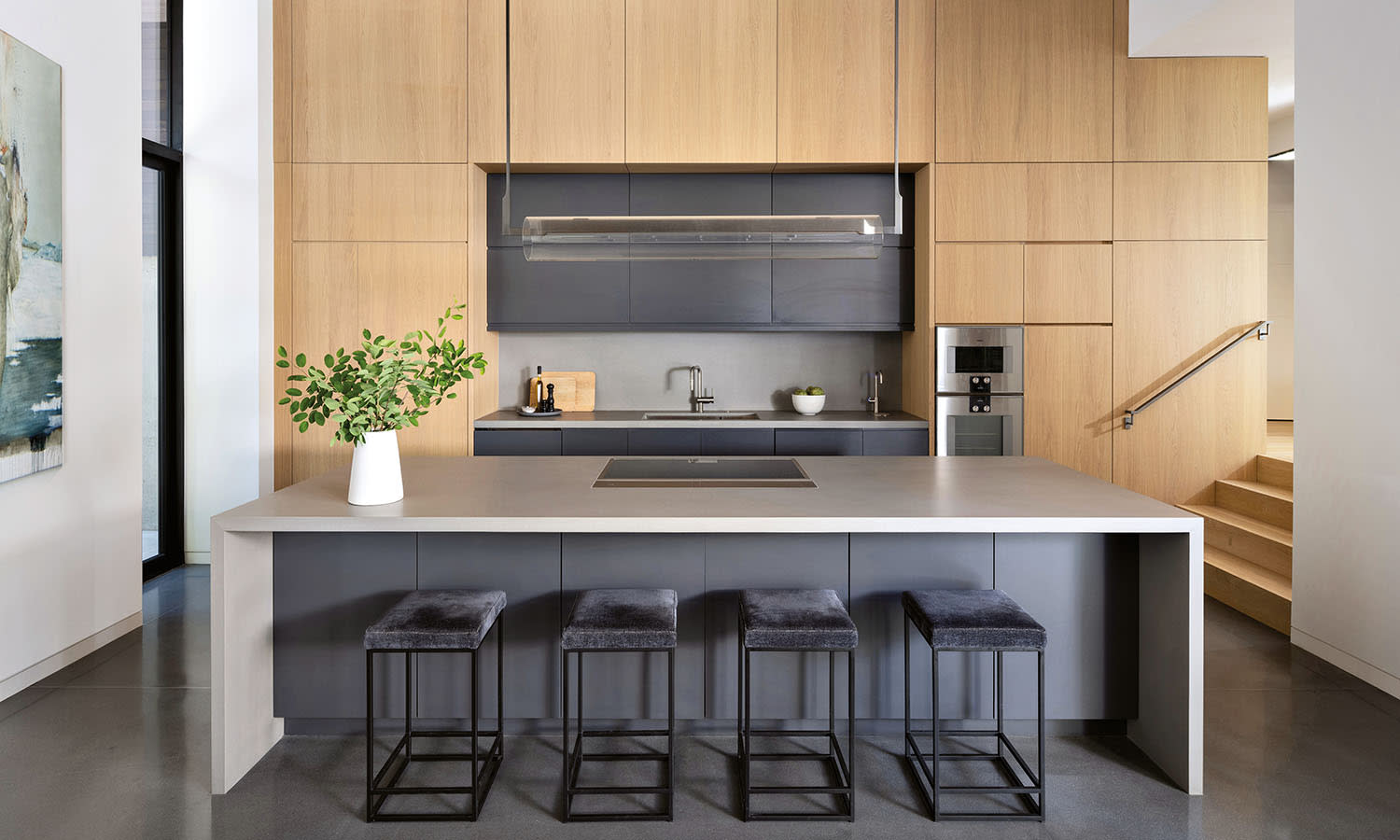 Modern kitchen with a sleek design featuring a gray island with four stools and minimalist cabinetry