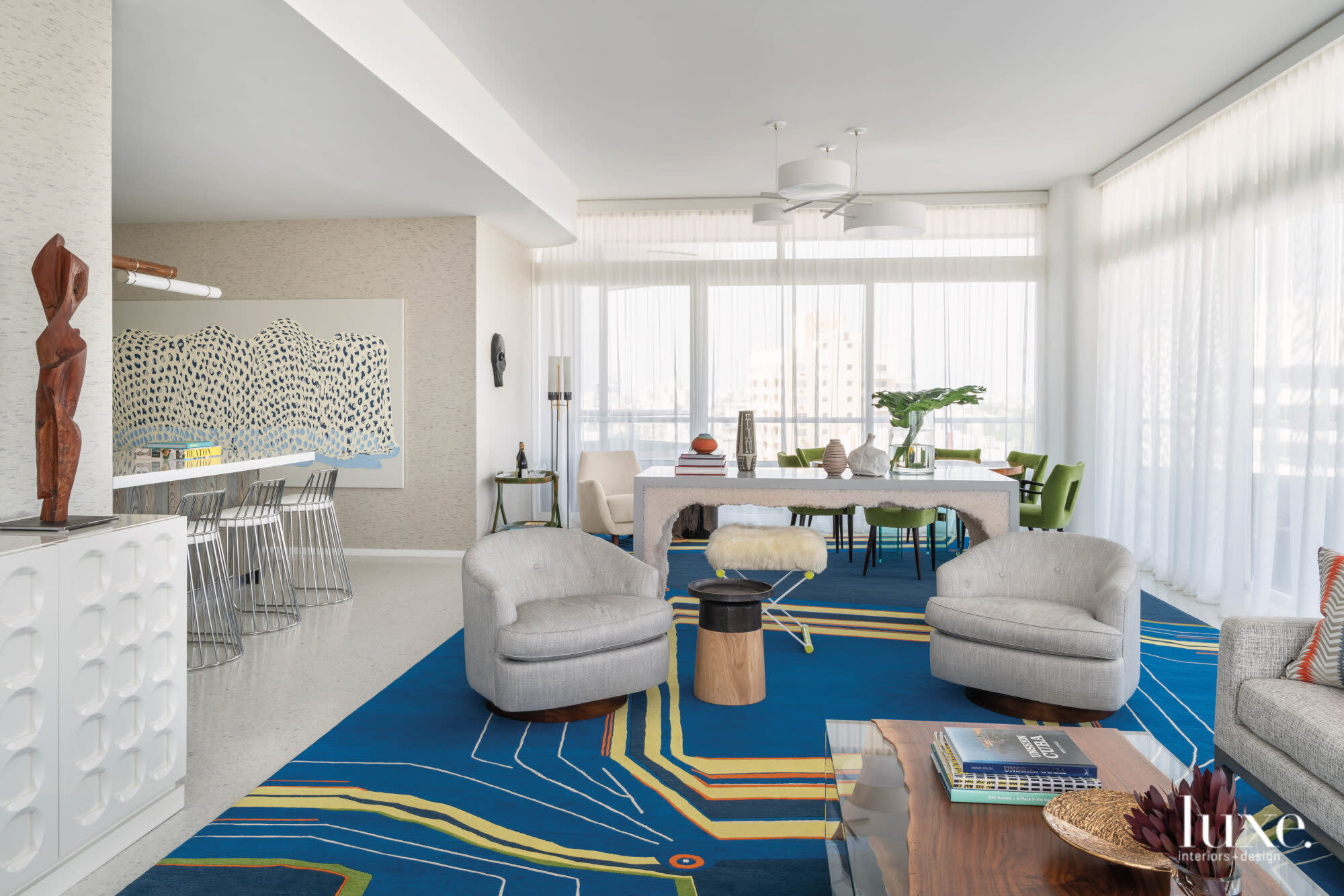 Great room with blue and yellow rug, gray armchairs and a rock salt console table