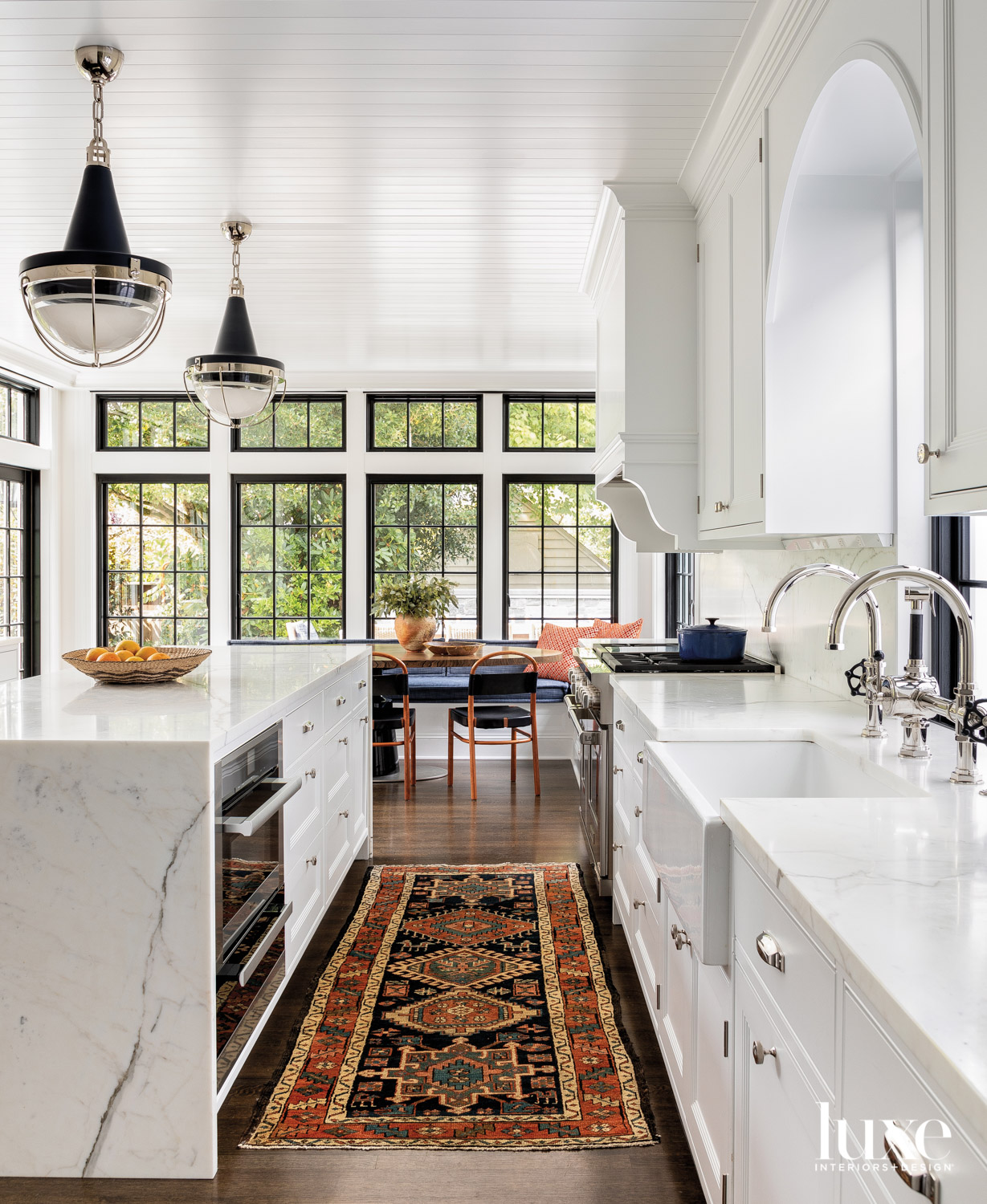 marble topped island with pendants above facing a window and dining area