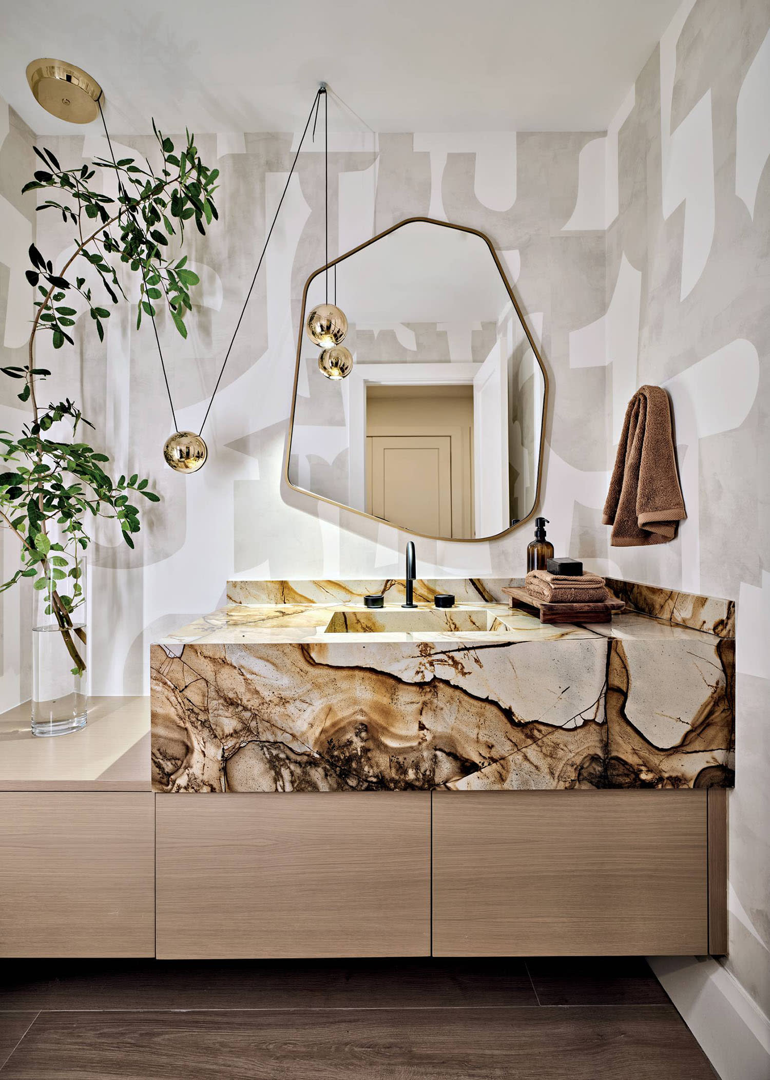 brown and white marble sink under an irregular-shaped mirror in a modern powder room