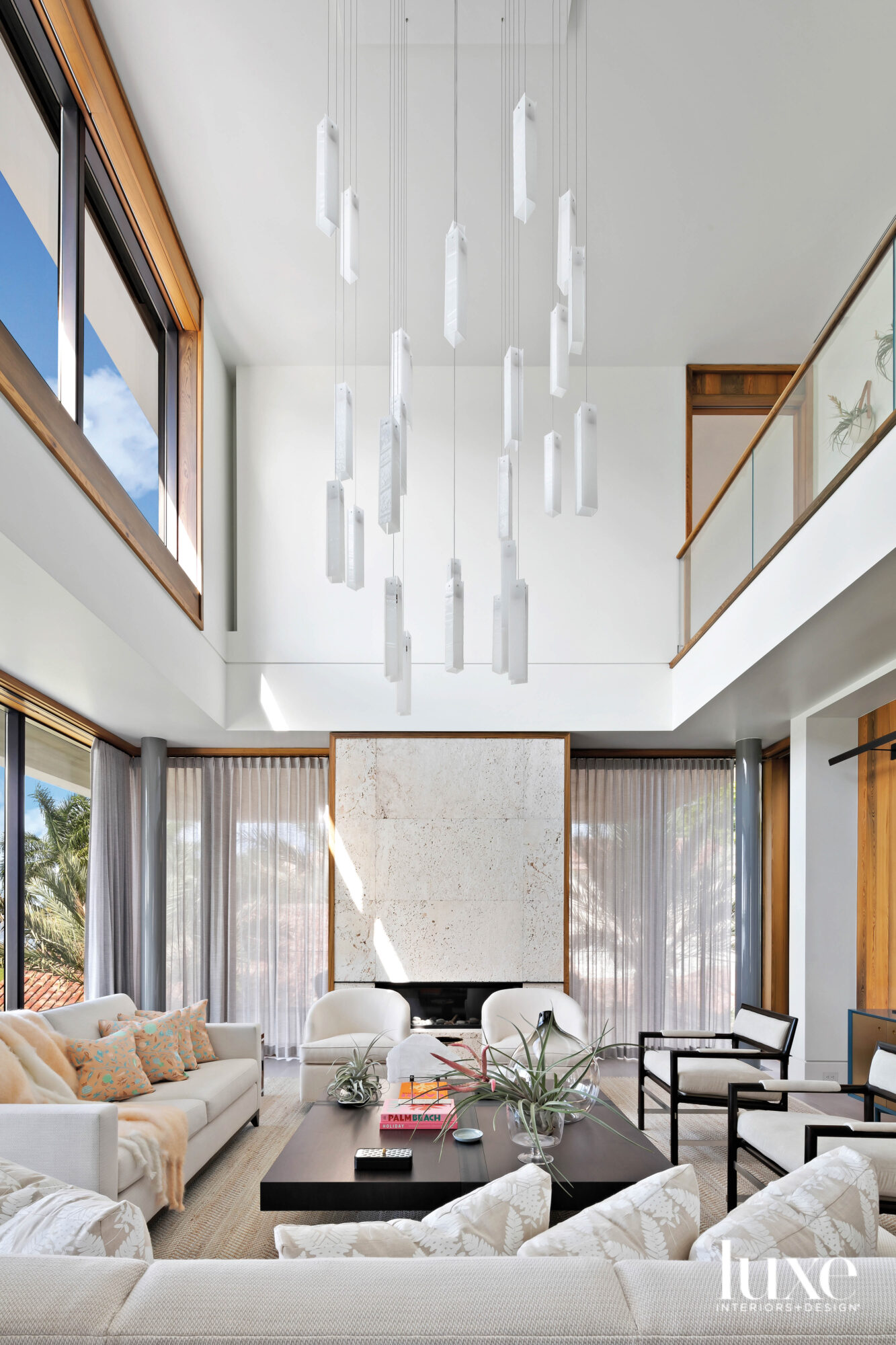 Double-height living room with chandelier and fireplace.