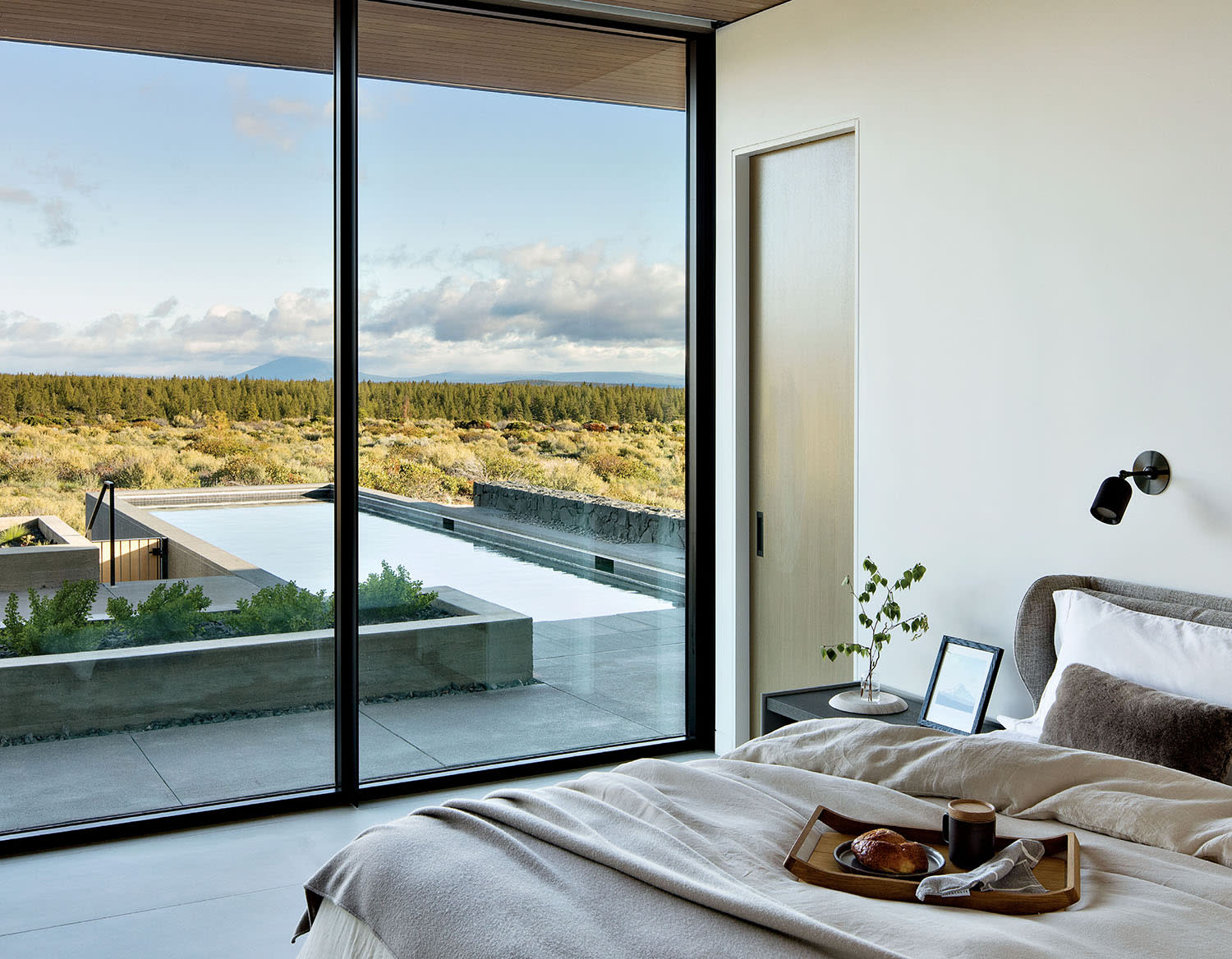 modern Oregon home's guest room with floor-to-ceiling windows framing the landscape outside