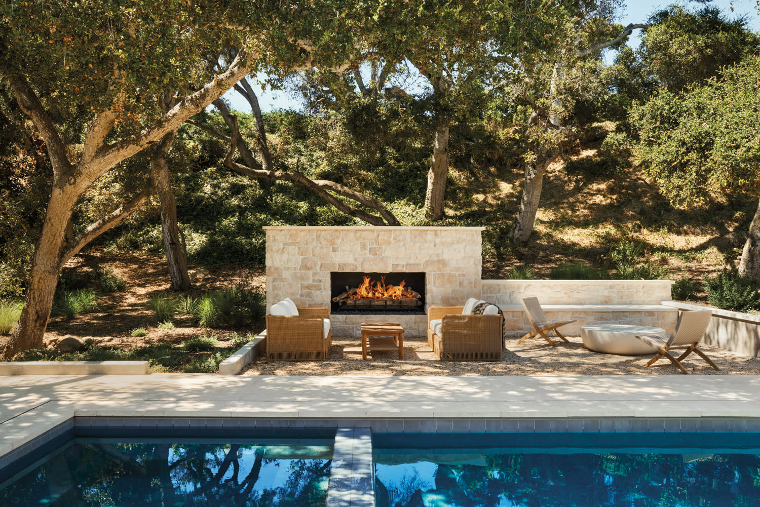 hardscape surrounding a home pool in Montecito with a limestone-surrounded fireplace