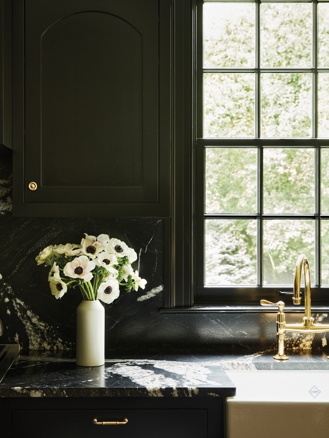 black kitchen cabinets with marble counter and brass tap