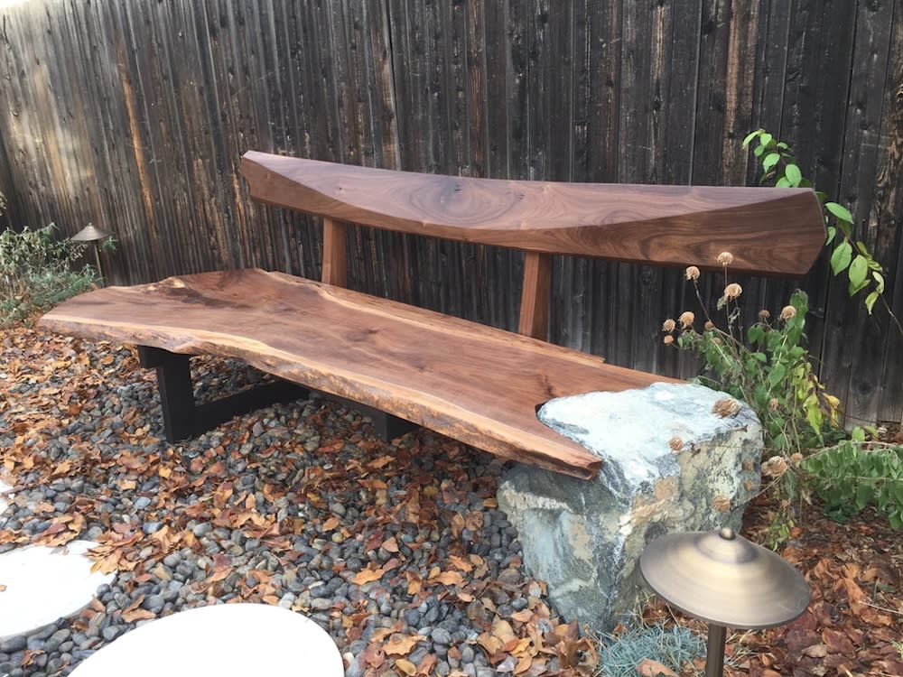 Dark natural wood bench in outdoor rock garden.