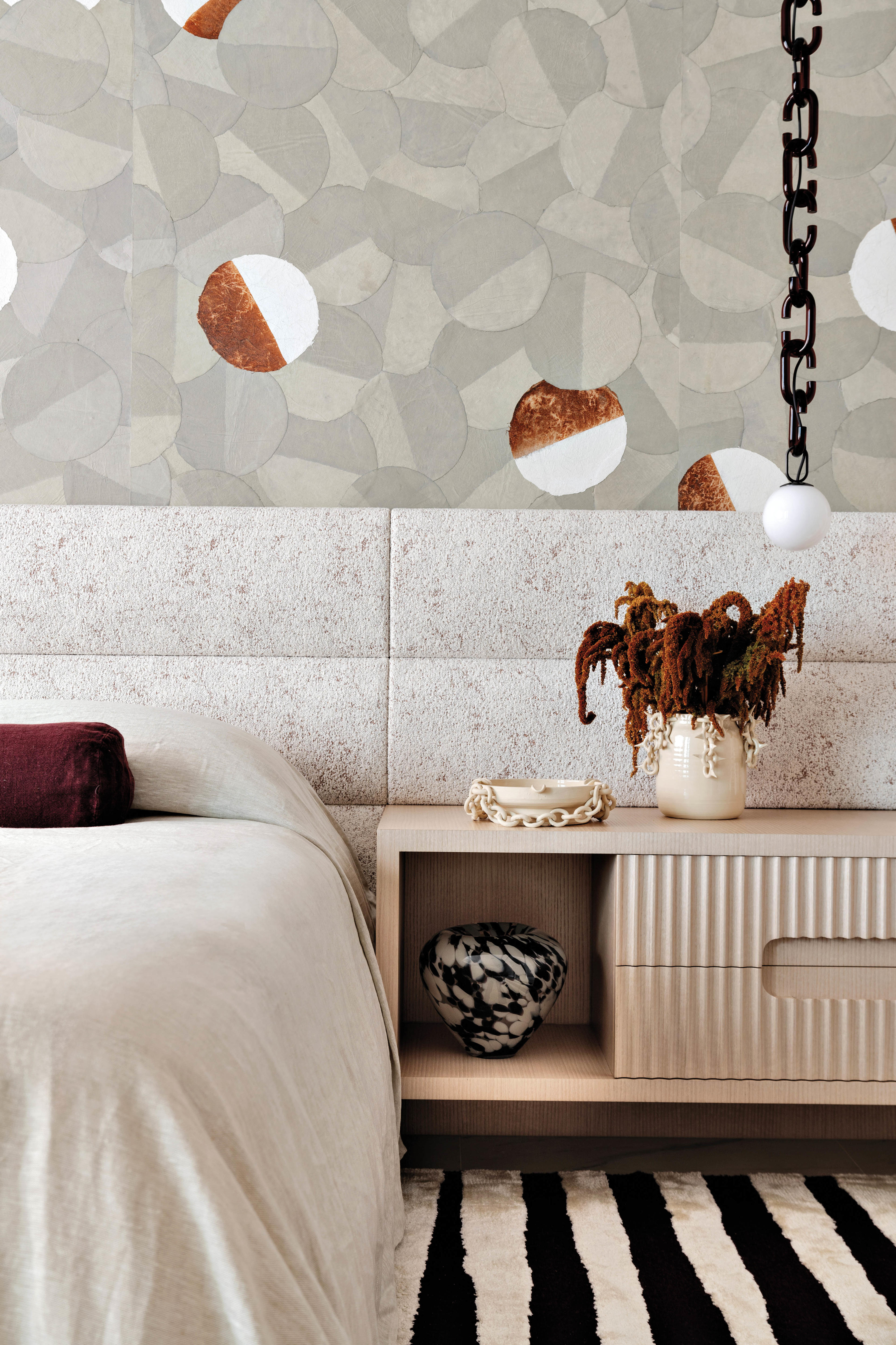 modern neutral bedroom with a chan-like chandelier and a graphic wallcovering 