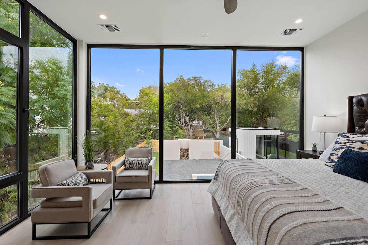 A bedroom with expansive windows showcasing a scenic outdoor view.