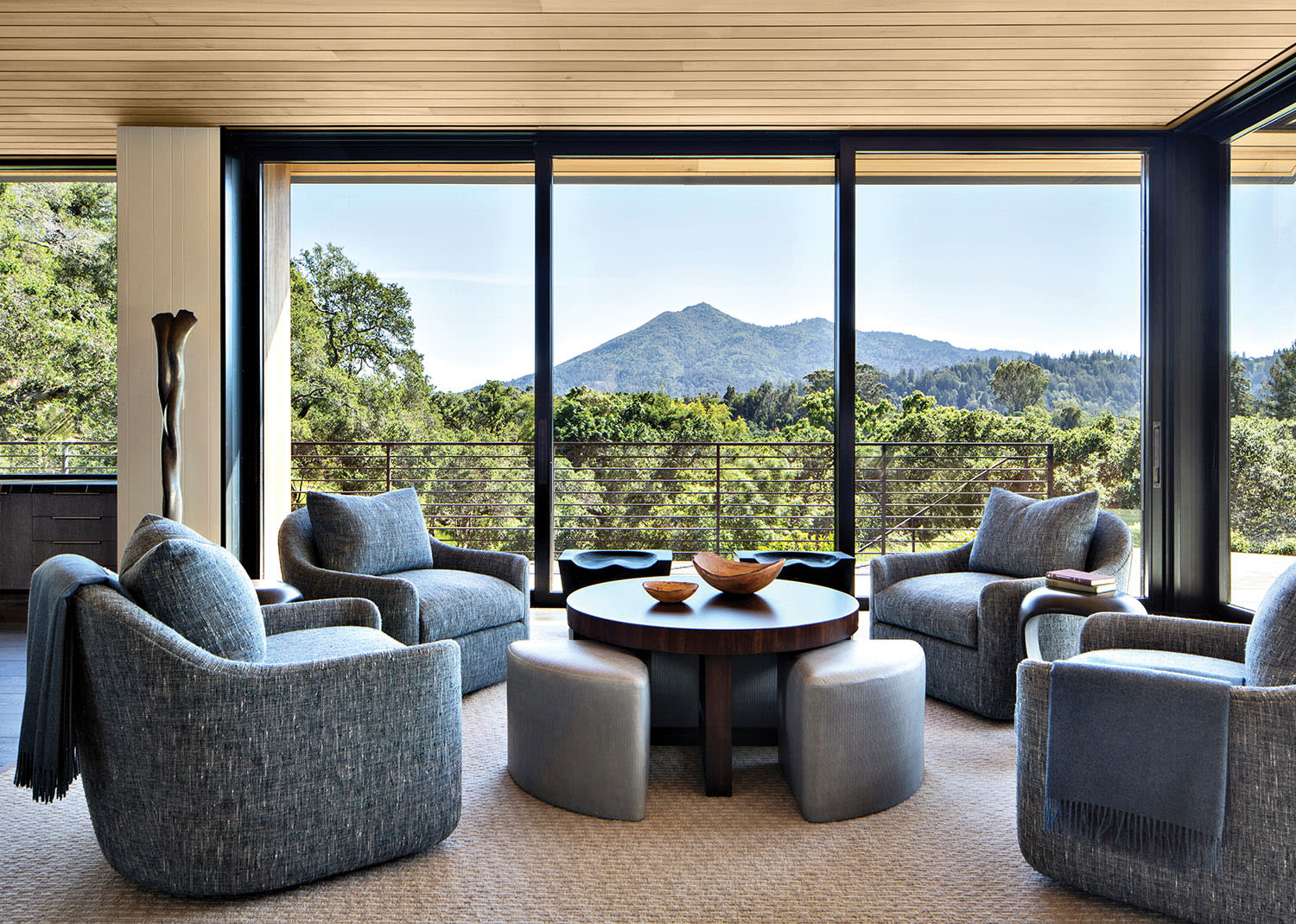 modern family room with blue armchairs and lush landscape views through large windows