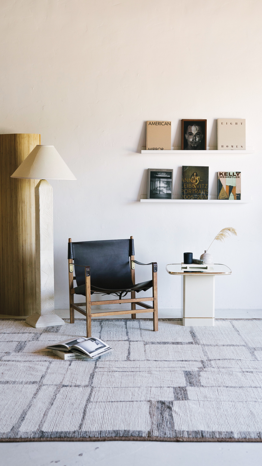 corner of a shop with leather-and-wood armchair, floor lamp and white side table