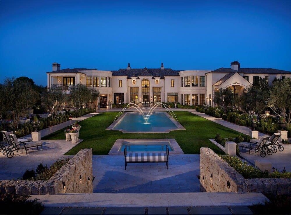 Backyard of grande home with pool, water fountains and manicured lawns