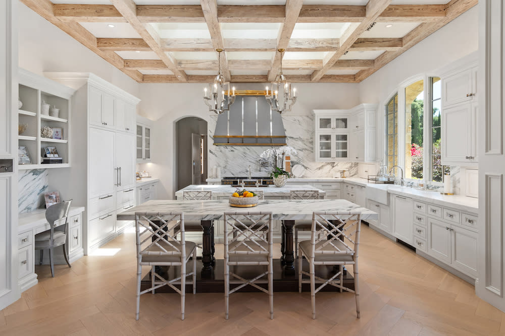 A stylish kitchen showcasing a polished marble island complemented by a beautiful chandelier, enhancing the overall decor.