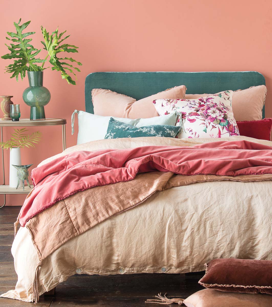 Bed with green headboard and pink and neutral linens