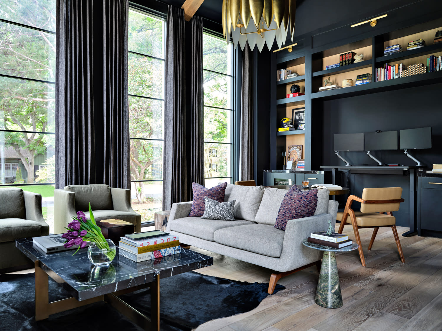 moody study with dark blue walls and a gold chandelier