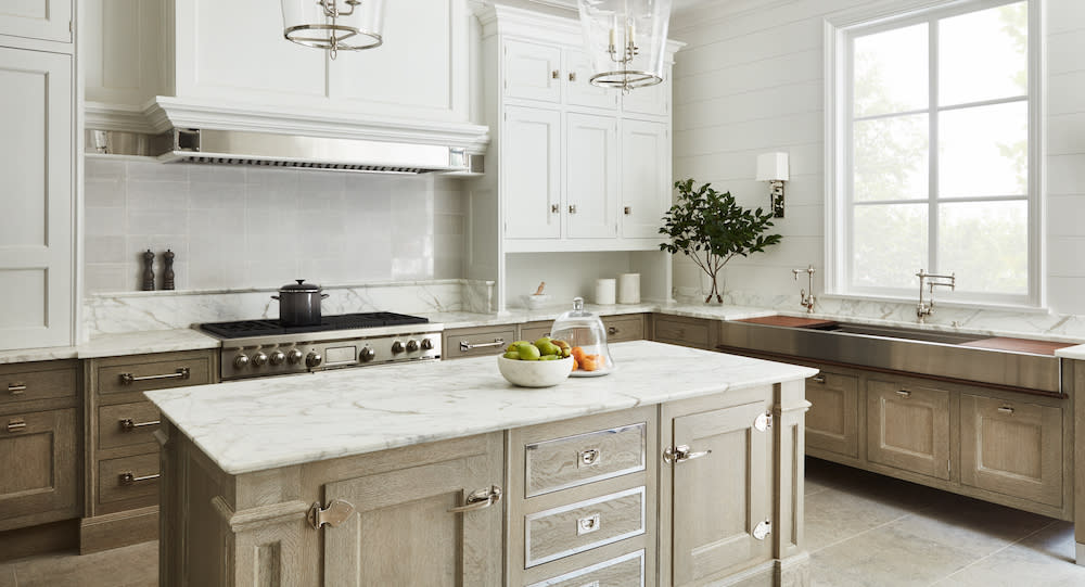 White upper cabinets and Cerused oak lowers, white countertops and stainless steel apron sink.