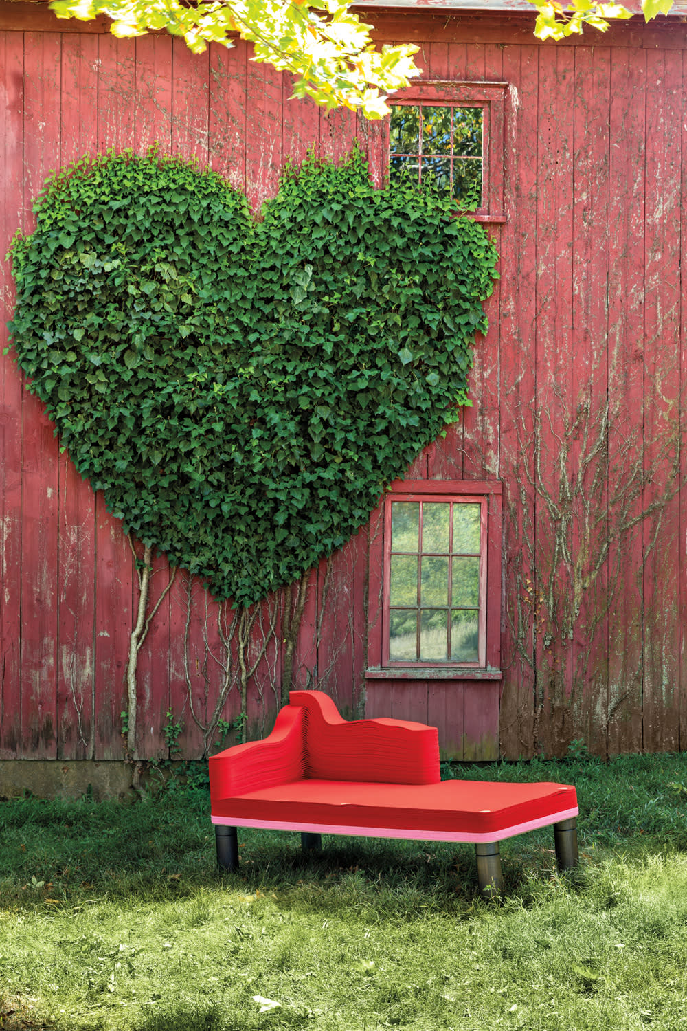 red Madame Chaise Lounge from repurposed materials in front of red barn with heart landcaping