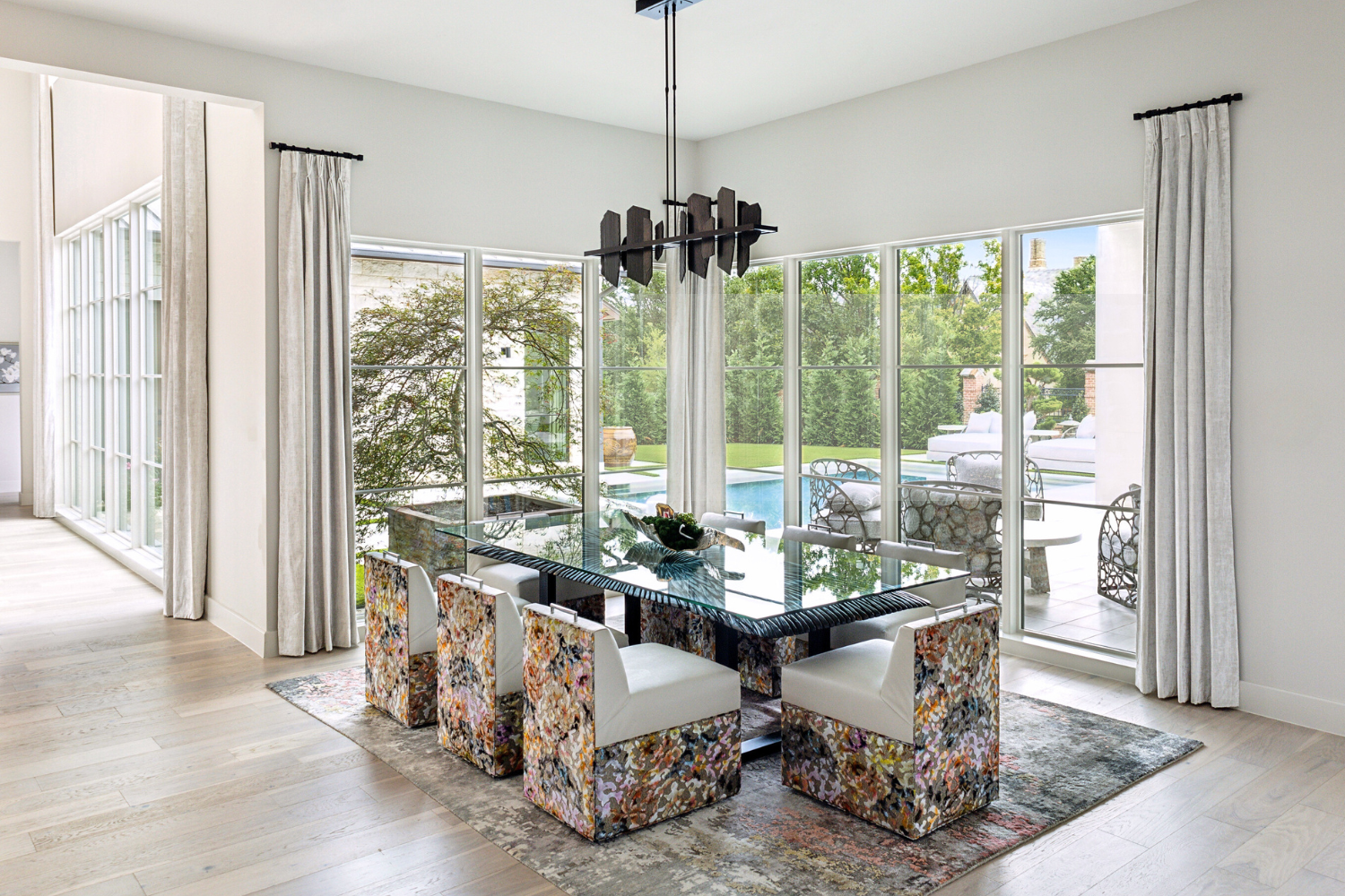 Bold in Bloom, Southlake: An elegant dining room with a large glass table and chic chairs, offering a bright and airy space for dining experiences.
