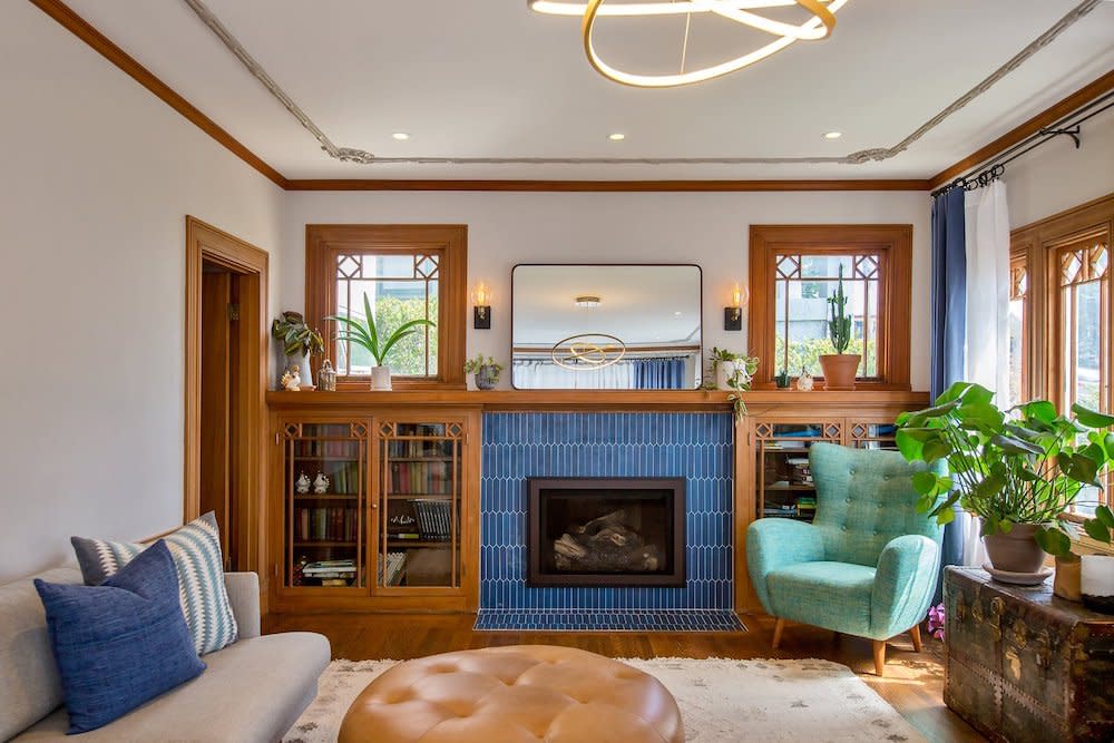 Living room with a focal point fireplace featuring striking blue tile surround, complemented by light wood built-in cabinets. The room exudes warmth and sophistication with its harmonious blend of textures and colors, inviting relaxation and comfort.