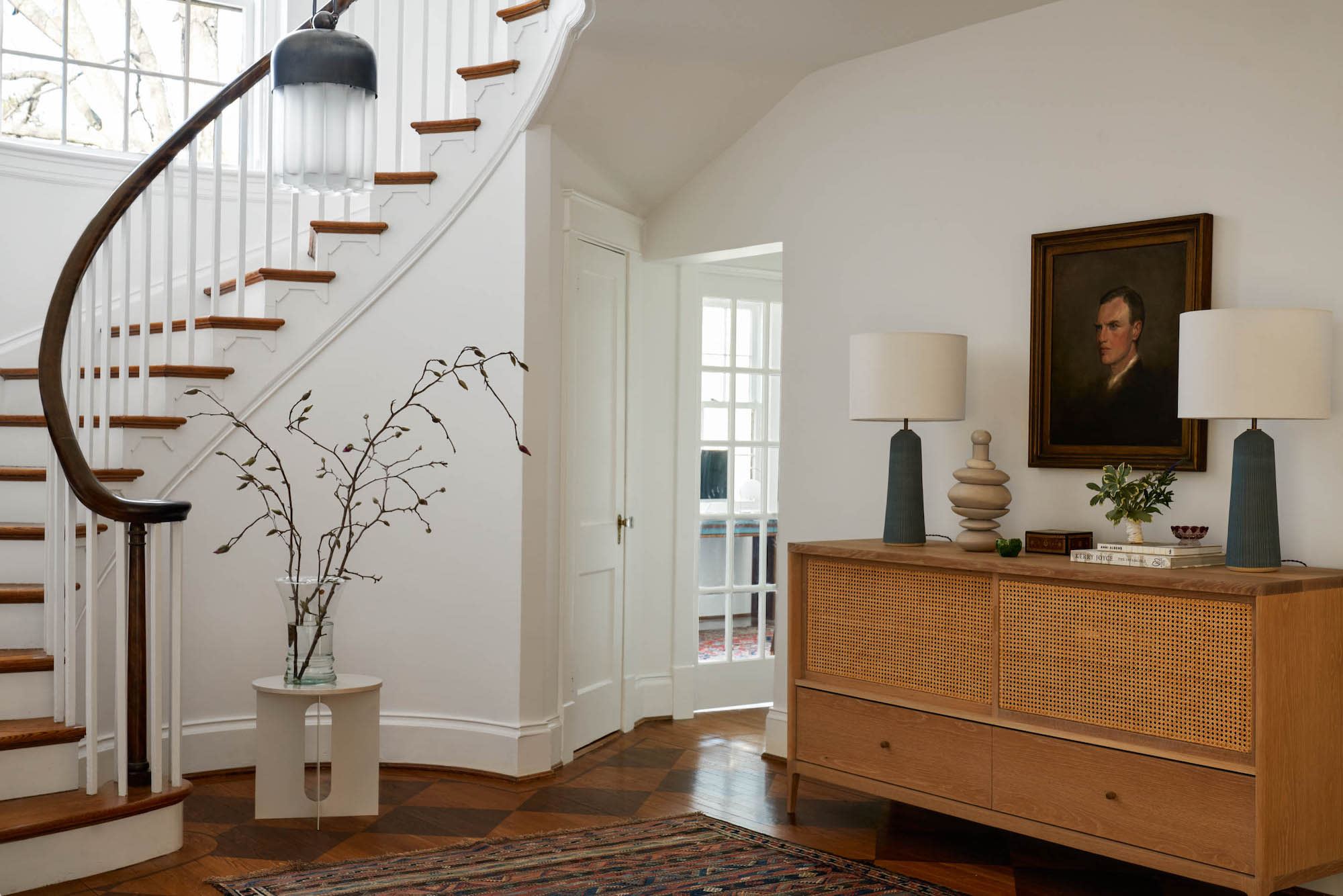 A traditional entry with wood end table at bottom of staircase.