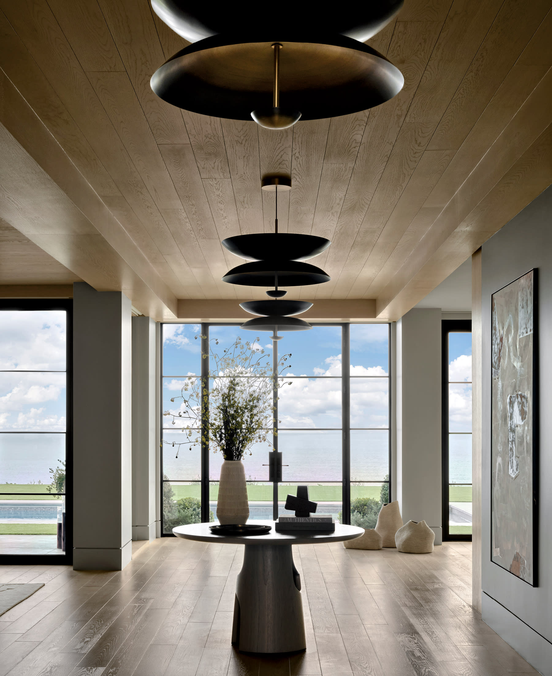 contemporary entryway with a walnut table in the center and views of the ocean beyond