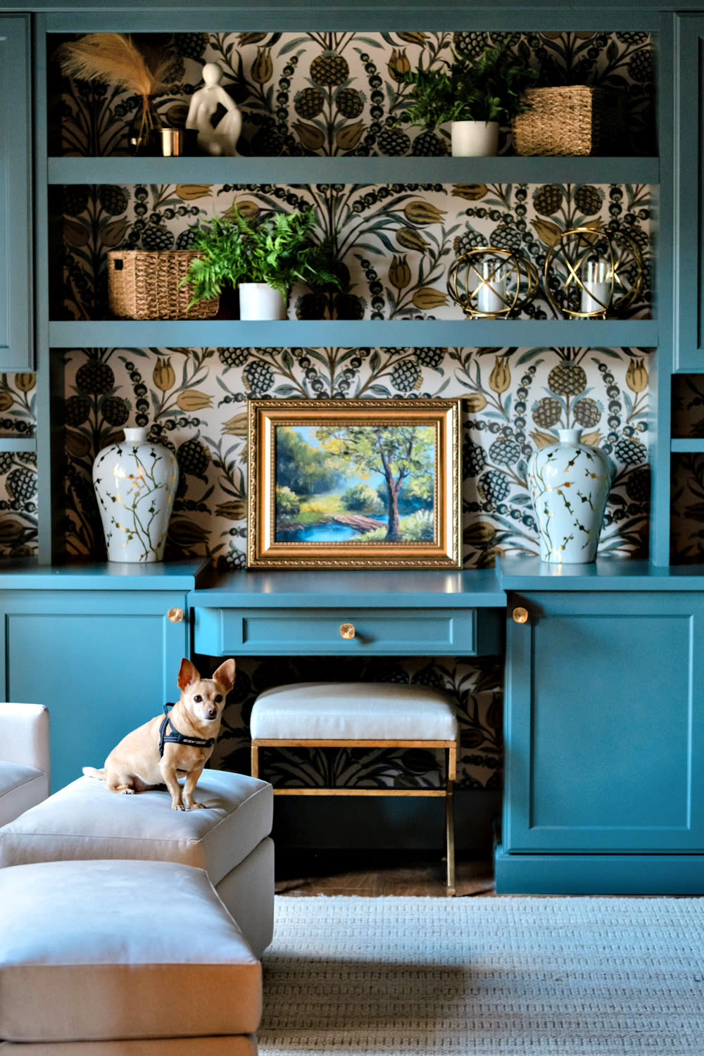 living space vignette of a built in blue shelf with floral wallpaper lining the back